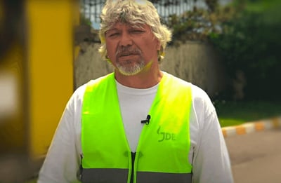 Румен Димитров, оператор на пекарна, стои с жълта жилетка пред кафе фабриката Nova Brasilia