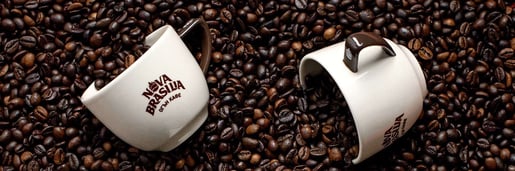 Две чаши за кафе върху кафе на зърна от Nova Brasilia
