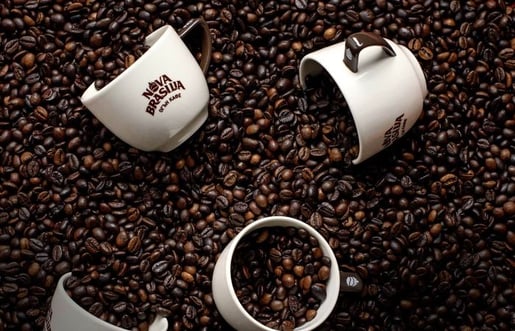 Две чаши за кафе върху кафе на зърна от Nova Brasilia