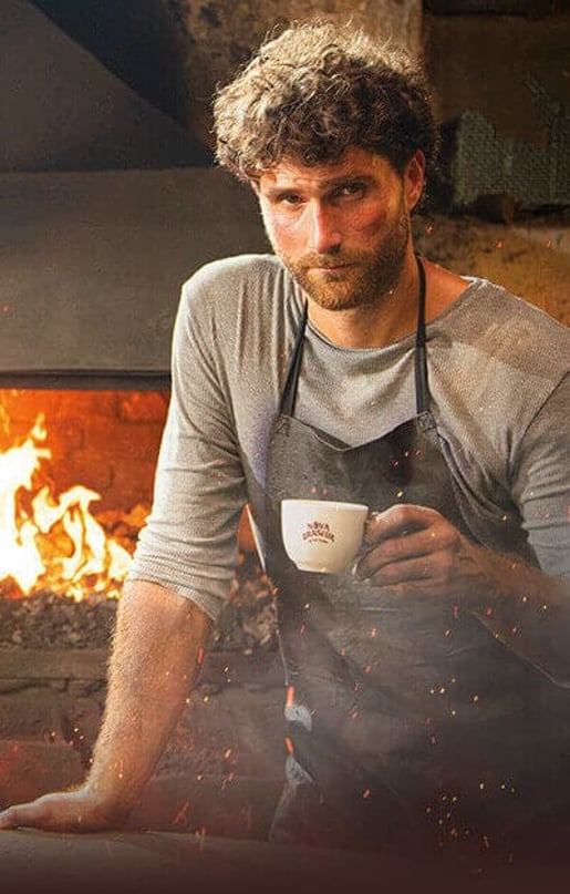 Мъж, стоящ пред камина, наслаждаващ се на чаша кафе от Nova Brasilia